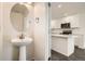 Stylish half-bathroom with a modern pedestal sink and an adjacent view into the home's bright, contemporary kitchen at 10331 E 62Nd Pl, Denver, CO 80238