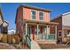 Charming two-story home features a welcoming front porch with teal railing and a vibrant coral exterior at 10331 E 62Nd Pl, Denver, CO 80238