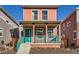 Charming two-story home features a welcoming front porch with teal railing and a vibrant coral exterior at 10331 E 62Nd Pl, Denver, CO 80238