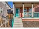 Inviting front porch with teal railings and a matching front door and concrete steps to welcome visitors at 10331 E 62Nd Pl, Denver, CO 80238