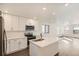 Open-concept kitchen featuring white cabinetry, stainless steel appliances, quartz countertops, and a functional island at 10331 E 62Nd Pl, Denver, CO 80238