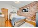 Bedroom with exposed brick wall, hardwood floors, and a cozy blue patterned quilt on the bed at 4673 Bryant St, Denver, CO 80211