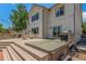 Home's backyard features a spacious deck with a hot tub, ample seating, mature trees, and string lights at 11256 Lima St, Commerce City, CO 80640