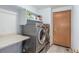 Bright laundry room with front loading washer/dryer, tiled floor, built-in shelves, and access to outside entry at 11256 Lima St, Commerce City, CO 80640