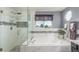 Bright bathroom featuring a soaking tub, separate shower, and stylish gray accents at 11256 Lima St, Commerce City, CO 80640