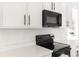Close-up of a modern kitchen featuring white cabinets and sleek black appliances with ample counter space at 16423 Mountain Flax Dr, Monument, CO 80132