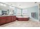 Bright bathroom featuring a soaking tub, dual vanity, and ample natural light from two large windows at 11938 S Meander Way, Parker, CO 80138