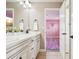 Well-lit bathroom featuring dual sinks, white cabinets, and a doorway leading to a pink-themed bedroom at 11938 S Meander Way, Parker, CO 80138