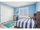 Blue-themed bedroom with a comfortable striped bed, dinosaur wall sticker, and a bright shuttered window at 11938 S Meander Way, Parker, CO 80138