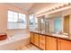 Well-lit bathroom features double sinks, soaking tub, and large window overlooking mature trees at 2847 Mount Royal Dr, Castle Rock, CO 80104