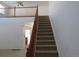 Carpeted staircase with wooden railing leads to the second floor, complemented by natural light and a neutral color scheme at 3930 S Quatar St, Aurora, CO 80018