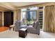 Sun-filled living room offers city views through large windows with seating and a dark wood cabinet at 1777 Larimer St # 902, Denver, CO 80202