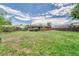 Spacious backyard with grass, full perimeter fence, red brick home, and small trees around the perimeter at 3463 W Bowles Ave, Littleton, CO 80123