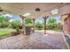 Covered outdoor patio with brick flooring, wood support beams, and well maintained green backyard with some foliage at 3463 W Bowles Ave, Littleton, CO 80123