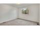 A bright bedroom featuring neutral carpet, white walls, and a window overlooking a backyard space at 10450 W 81St Pl, Arvada, CO 80005