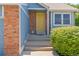 Entryway featuring a bright yellow front door, brick columns, and well-maintained landscaping at 9917 Garland Dr, Broomfield, CO 80021