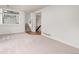 Bright living room featuring neutral carpet, white walls, and staircase access at 9917 Garland Dr, Broomfield, CO 80021