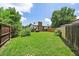 Wide view of a spacious, enclosed backyard with healthy lawn, a brick chimney, and a wooden fence at 1018 Kelly Pl, Longmont, CO 80501