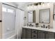 Bathroom with double sink vanity, gray cabinets, tub and shower, and modern lighting fixtures at 4241 Brookwood Pl, Highlands Ranch, CO 80130