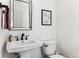 Bathroom featuring pedestal sink, black faucet, a framed mirror, toilet, and artwork at 4241 Brookwood Pl, Highlands Ranch, CO 80130