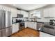 Kitchen boasts stainless steel appliances, granite counters, white cabinetry, and hardwood floors at 4241 Brookwood Pl, Highlands Ranch, CO 80130