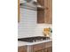 Close-up of a gas range with stainless-steel hood and subway tile backsplash at 81 Simmental Loop, Castle Rock, CO 80104