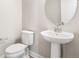 Bright half bathroom features pedestal sink, oval mirror and a white toilet at 21127 E 62Nd Dr, Aurora, CO 80019