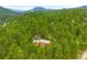 Stunning aerial view of a house surrounded by a sea of green trees and rolling hills with mountain views at 9633 Fox Valley Dr, Morrison, CO 80465