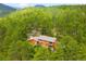 Aerial view of a charming home nestled among lush green trees with mountains visible in the background at 9633 Fox Valley Dr, Morrison, CO 80465