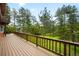 Large wooden deck with railing overlooking a backyard forest at 9633 Fox Valley Dr, Morrison, CO 80465