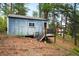 Exterior view of a small, blue, wood-sided building in a wooded area, with an open door and small deck at 9633 Fox Valley Dr, Morrison, CO 80465