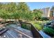 Wooden back deck overlooking a pond with a waterfall feature and mature trees at 13844 E Lehigh Ave # H, Aurora, CO 80014