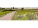 Walking path winding through a grassy field with mature trees and shrubs on a partly cloudy day at 13844 E Lehigh Ave # H, Aurora, CO 80014