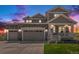 Charming two-story home features a stone facade, three-car garage, and inviting front porch with landscaped yard at dusk at 1282 Eldorado Dr, Superior, CO 80027