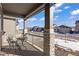 Covered porch with stone columns, a small table and chairs, and a view of a residential street at 6211 Leilani Ln, Castle Rock, CO 80108