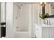 Bright bathroom features a shower-tub combo, all white tile and finishes, and updated fixtures at 4883 Perry St, Denver, CO 80212