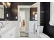 A monochromatic bathroom features contrasting black walls and white fixtures, tiled floor, and is well lit with modern sconces at 4883 Perry St, Denver, CO 80212