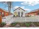Quaint home with a well manicured lawn framed by a white picket fence and mature tree at 4883 Perry St, Denver, CO 80212