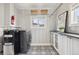 Bright laundry room with gray appliances and white cabinets with black countertops at 4883 Perry St, Denver, CO 80212