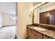 Bathroom with wood vanity, sink with granite counters, and large mirror at 2056 S Newark Way, Aurora, CO 80014
