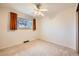 Bright bedroom features carpeted floors, a ceiling fan and a window overlooking the yard at 2056 S Newark Way, Aurora, CO 80014