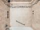 Beige tile shower with black trim, a shower head, built-in shelf, and metal grab bar for safety at 2056 S Newark Way, Aurora, CO 80014