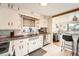 Well-lit kitchen with white cabinets, granite countertops, and a view into the living room at 7060 Avrum Dr, Denver, CO 80221