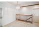 Hallway and stair landing with wood railing, neutral walls and a pendant light fixture at 3335 S Verbena Ct, Denver, CO 80231