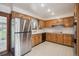 Kitchen with wood cabinets, white countertops, stainless steel refrigerator, and glass door to backyard at 3335 S Verbena Ct, Denver, CO 80231