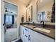 A modern bathroom featuring double vanity sinks with black hardware and an open doorway to the primary bedroom at 938 Larkspur Ln, Louisville, CO 80027