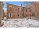 Rear exterior view of brick building, showing windows, a chimney, and a snow-covered yard at 125 E 11Th Ave # 2, Denver, CO 80203