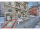 Brick building showcases the parking area for Unit #2, with brick landscaping, concrete sidewalk, and snowy accents at 125 E 11Th Ave # 2, Denver, CO 80203