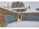 Attached two-car garage with wood exterior and snow on the ground at 12136 E 2Nd Dr, Aurora, CO 80011