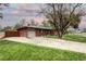 Charming brick home featuring an attached garage and large front yard with mature trees and a long driveway at 6365 S Valleyview St, Littleton, CO 80120